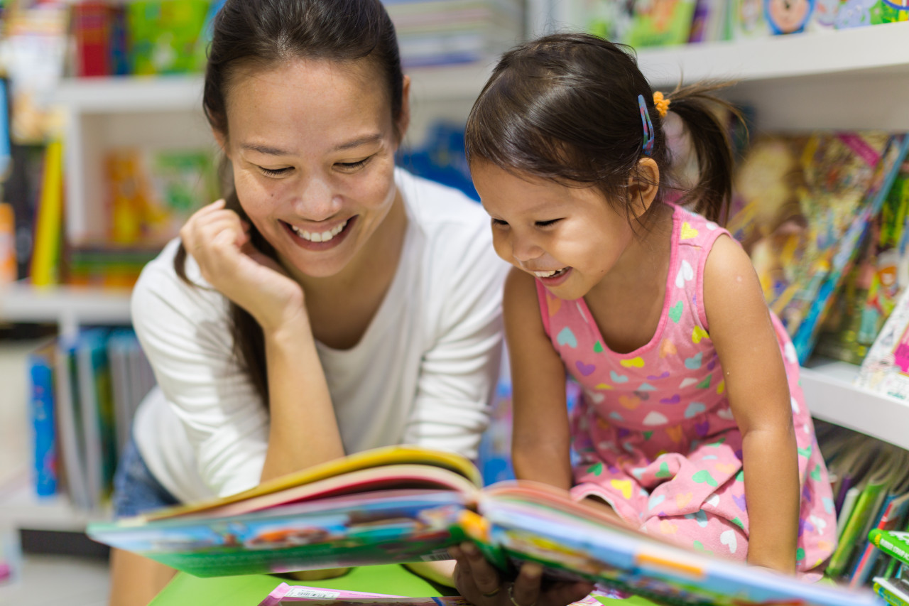 a mother and daughter on the floor reading a book together